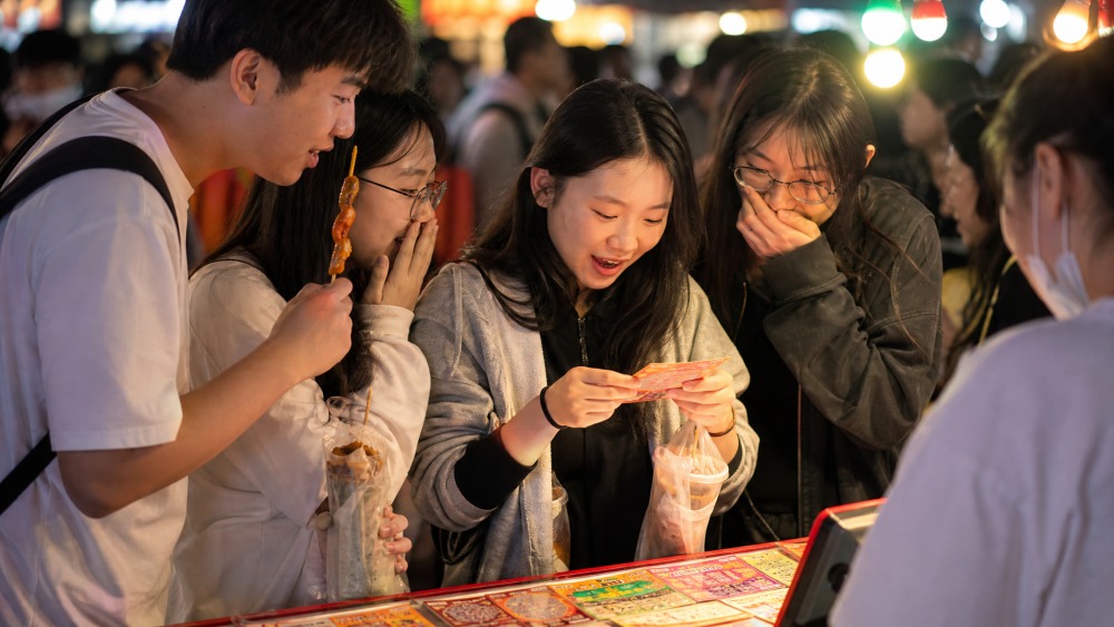烟台夜市多了刮刮乐摊位,逛完小吃的人顺手试试手气